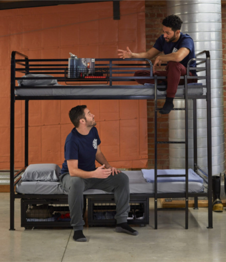 Two adults sitting on a heavy duty steel bunk bed rated to 225kg per platform